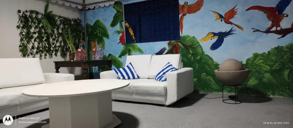 a living room with a white couch and a mural at Blue Hostel in Natal