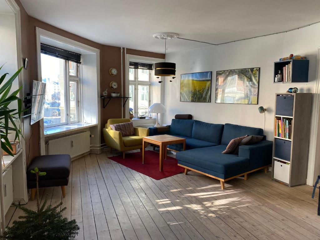 uma sala de estar com um sofá azul e cadeiras em Nice flat and area em Copenhaga