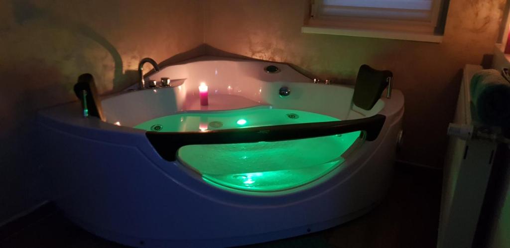 a bathroom with a green bathtub with a candle in it at Jacuzzi Room in Subotica