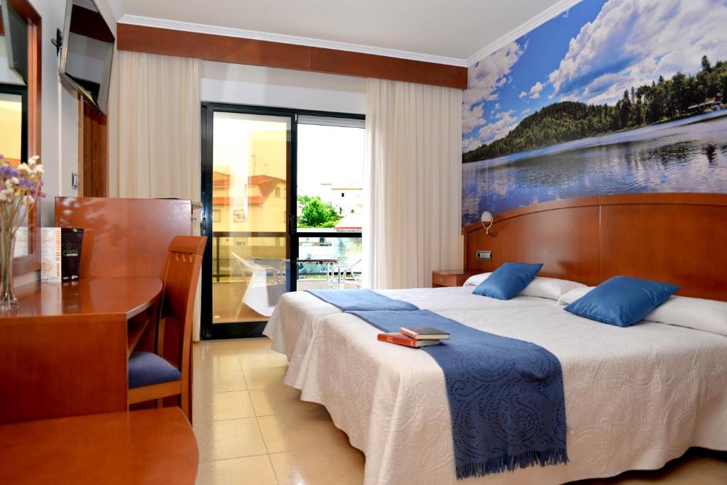 um quarto com uma cama, uma secretária e uma janela em Hotel Portonovo no Portonovo