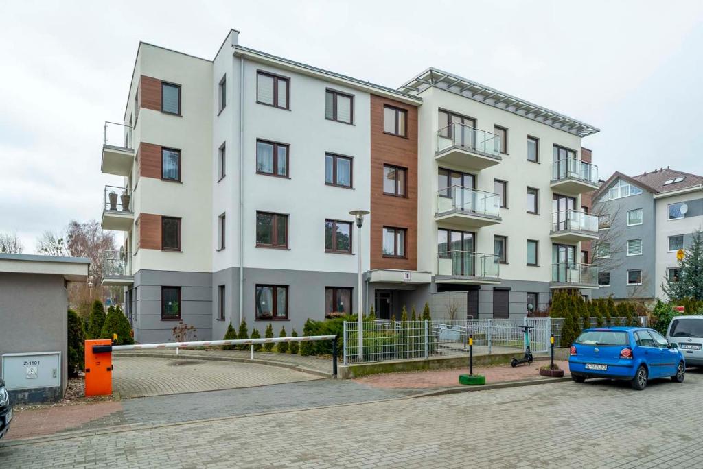 apartamentowiec z niebieskim samochodem zaparkowanym przed nim w obiekcie Apartamenty Aplauz we Władysławowie