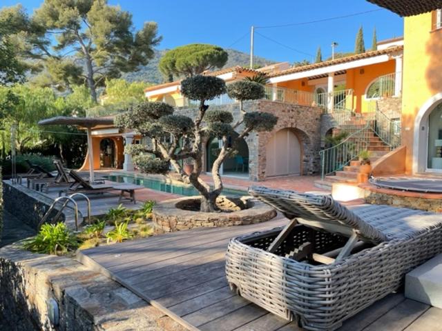 a house with a wooden deck with a bench and trees at VILLA LES PINS in Le Lavandou