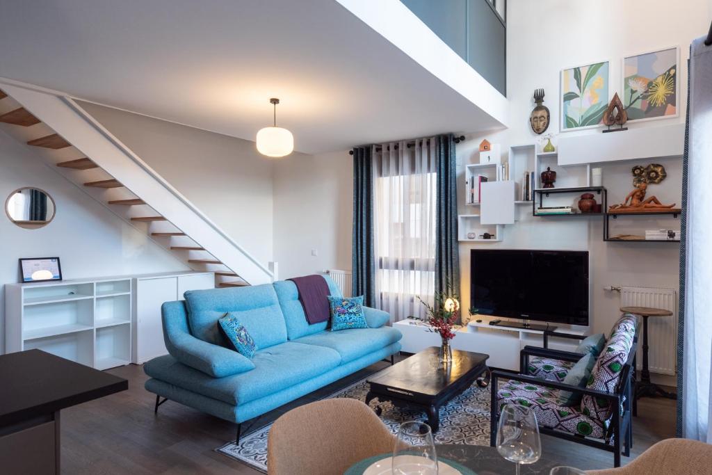 ein Wohnzimmer mit einem blauen Sofa und einem TV in der Unterkunft Vill'Arborea - Magnifique T3 au coeur du 7ème in Lyon