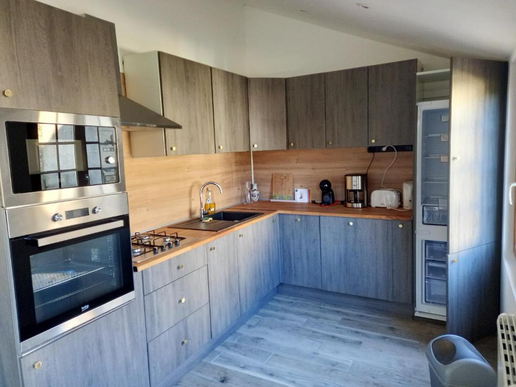 una cocina con armarios de madera y electrodomésticos de acero inoxidable en Maison de 3 chambres avec jardin clos et wifi a Quettehou, en Quettehou