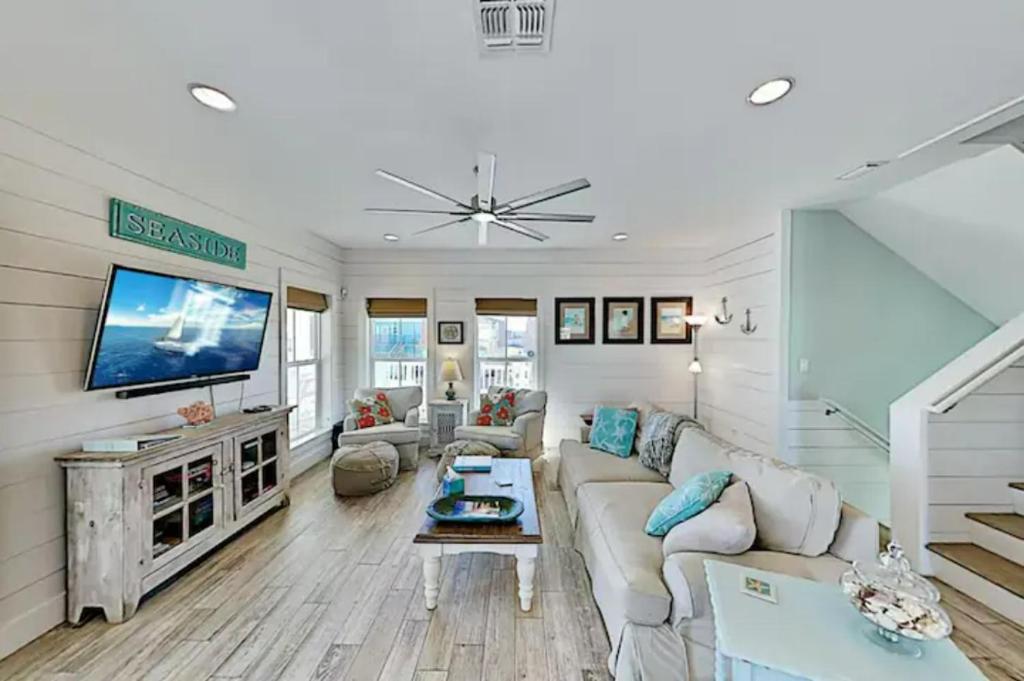 a living room with a couch and a tv at Steps to The Beach! Beautiful 4 BDRM 5 Bath Home W/Pool & Hot Tub in Port Aransas