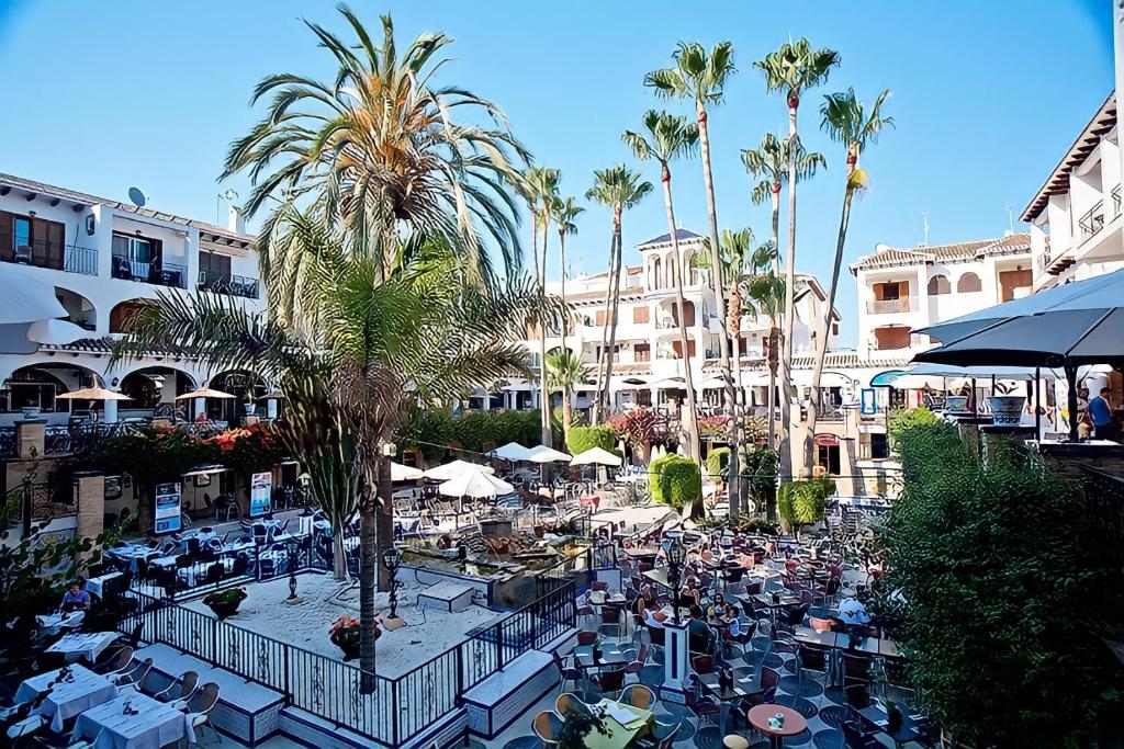 an outdoor patio with tables and chairs and palm trees at Apartment on the Plaza in Villamartin
