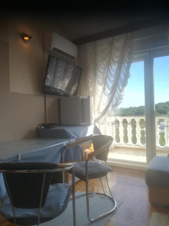 a room with a bed and a window with a balcony at Villa Verde Apartments and Rooms in Premantura