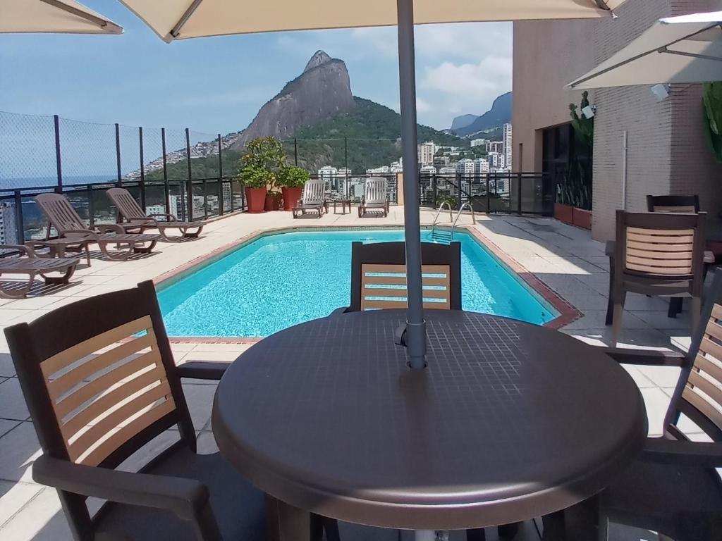una mesa con sombrilla y una piscina en TOP APART SERVICE's, en Río de Janeiro