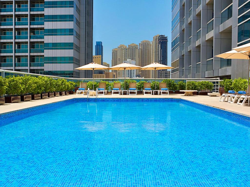 a large pool with chairs and umbrellas on a building at Armada Avenue Hotel - formerly Armada BlueBay Hotel in Dubai