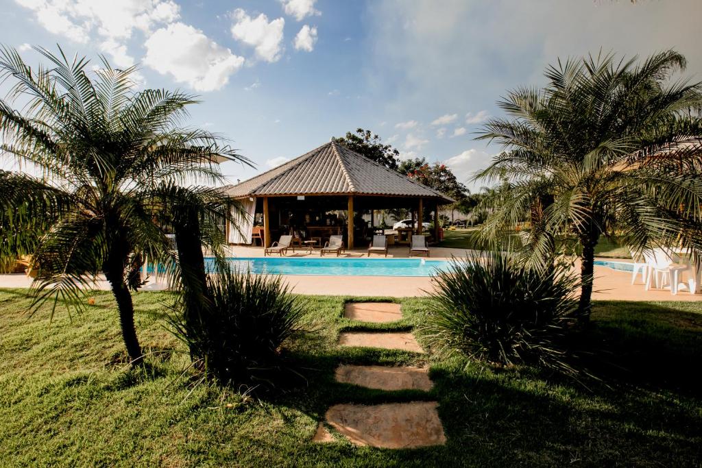 a house with a swimming pool and two palm trees at Pousada Pontal in Curvelo