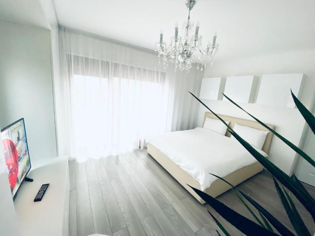 - une chambre blanche avec un lit et un lustre dans l'établissement Veneția Apartament - Timisoara, à Timişoara