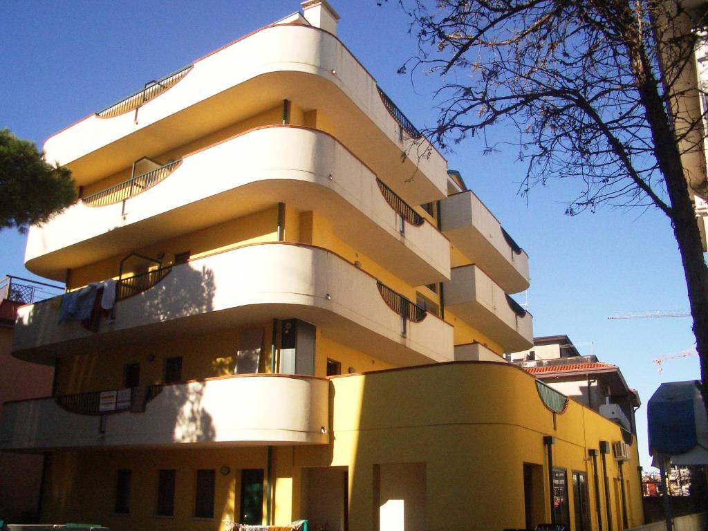 un edificio amarillo con balcones en un lateral en Residence Mediterraneo - Agenzia Cocal, en Caorle
