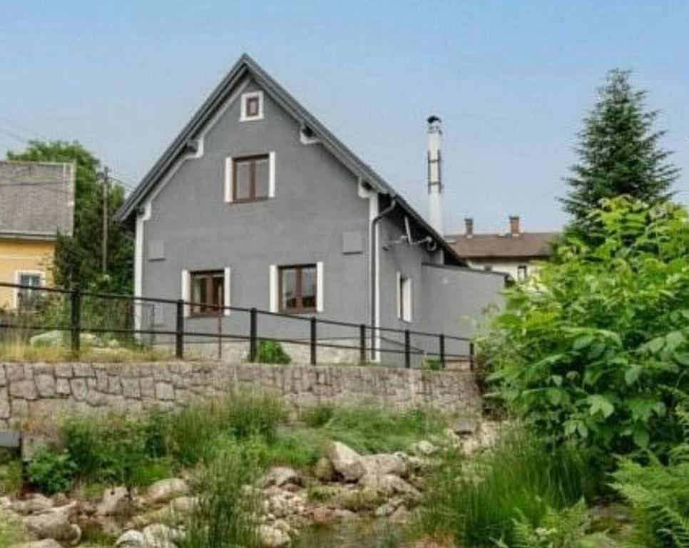 a large gray house with a stone retaining wall at Chalupa Pod Smědavou in Weissbach