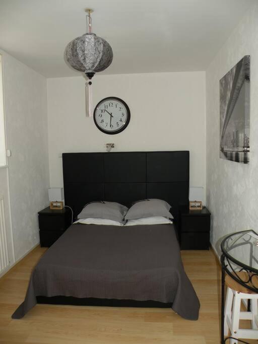 1 dormitorio con 1 cama con reloj en la pared en Charmant Studio à Belfort quartier Vosges, en Belfort