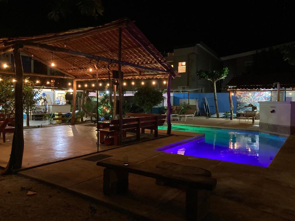 a swimming pool at night with a tent and a picnic table at TamaHostel & Glamping in Tamarindo