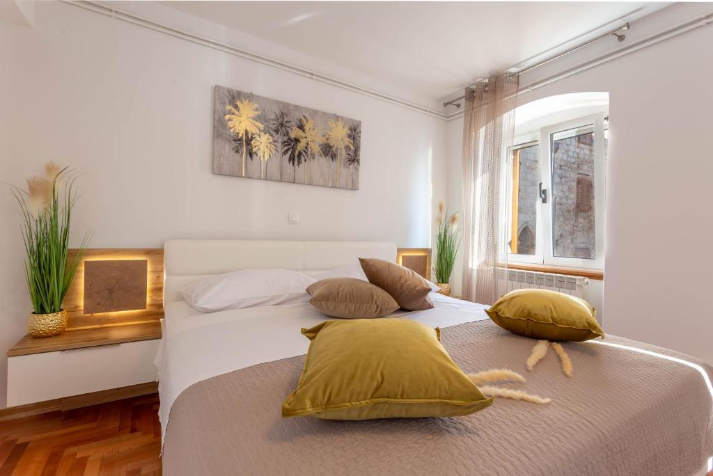 1 dormitorio con 1 cama blanca grande con almohadas amarillas en Deluxe Dreamy room in the Center of Hvar with Sea View en Hvar