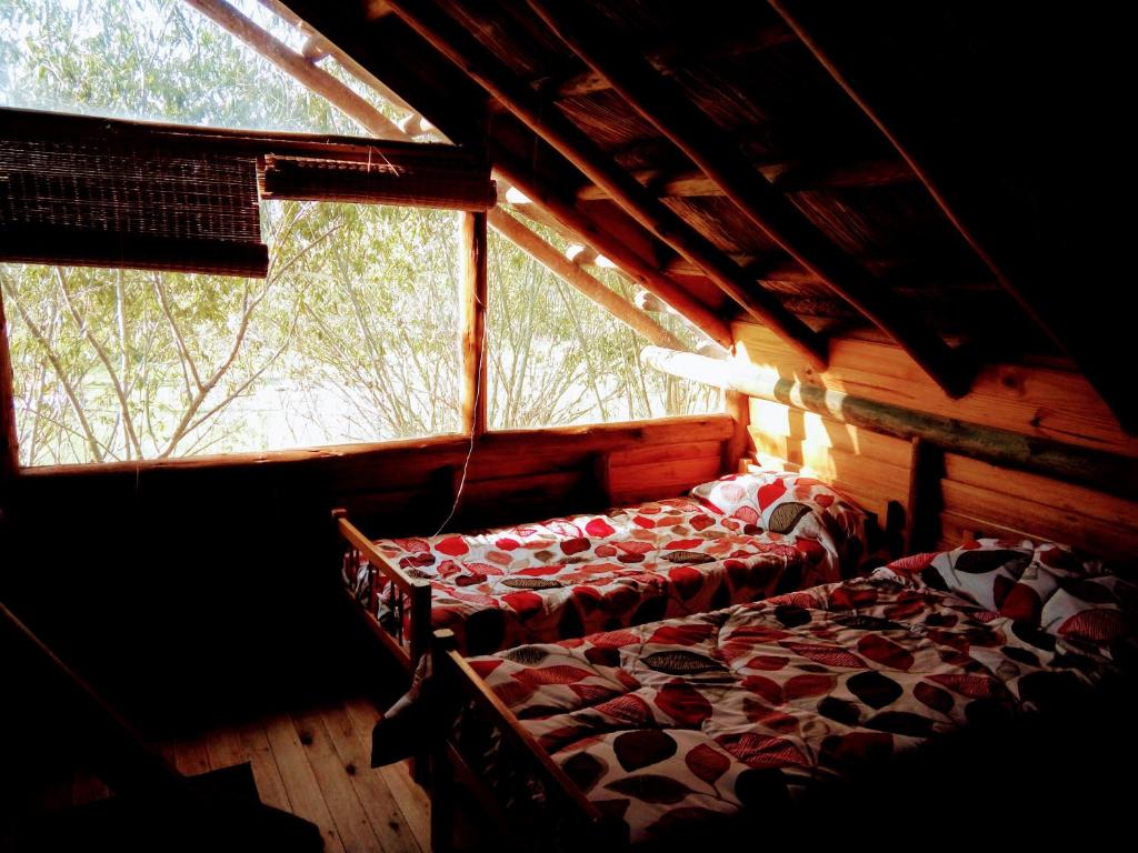 a bed in a room with a large window at Cabañas Manantiales de Obligado in San Pedro