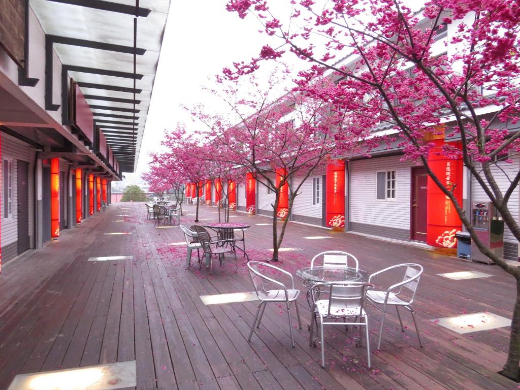 Sanyi Sakura Resort في ساني: فناء به طاولات وكراسي وأشجار بها ورد وردي