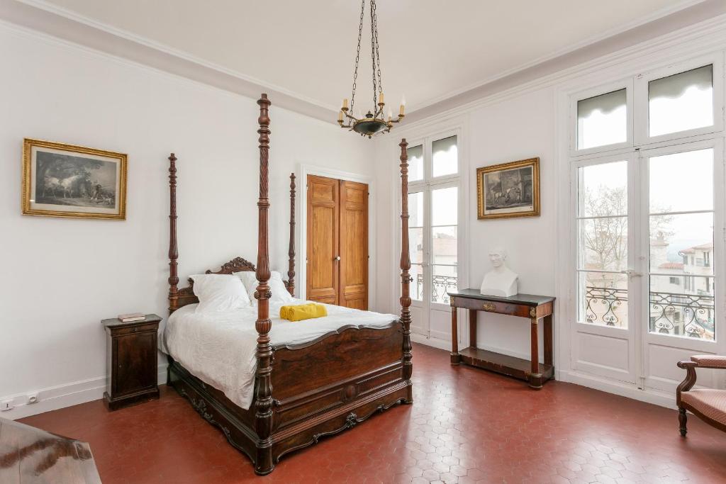 a bedroom with a bed and a table and windows at La Suite Napoléon 75m2 timeless stay in Béziers
