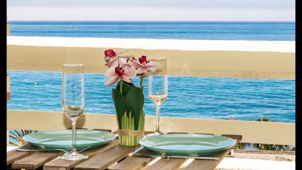 una mesa con dos platos y un jarrón con flores en BEACHFRONT APARTMENT In LA CALA DE MIJAS, en La Cala de Mijas