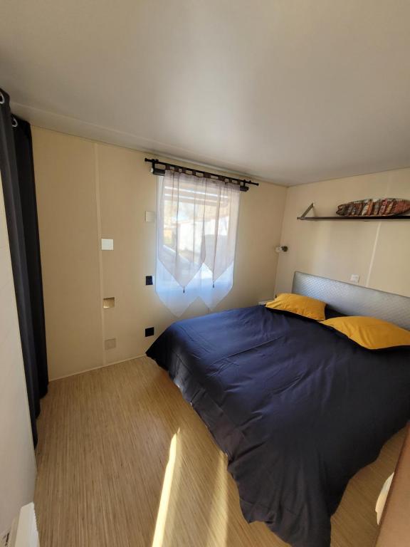 a bedroom with a blue bed and a window at Mobil Home Plage Lac Parentis&#47;Biscarosse in Parentis-en-Born