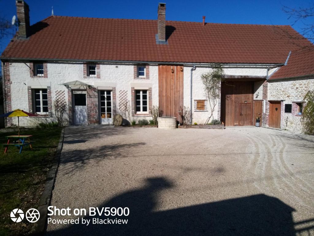 uma grande casa branca com uma entrada em frente em Chez Maman em Beugnon