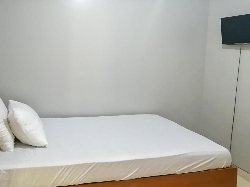 a bed with white sheets and pillows in a room at Griya Sakina Syariah near JIH Yogyakarta Mitra RedDoorz in Kejayan