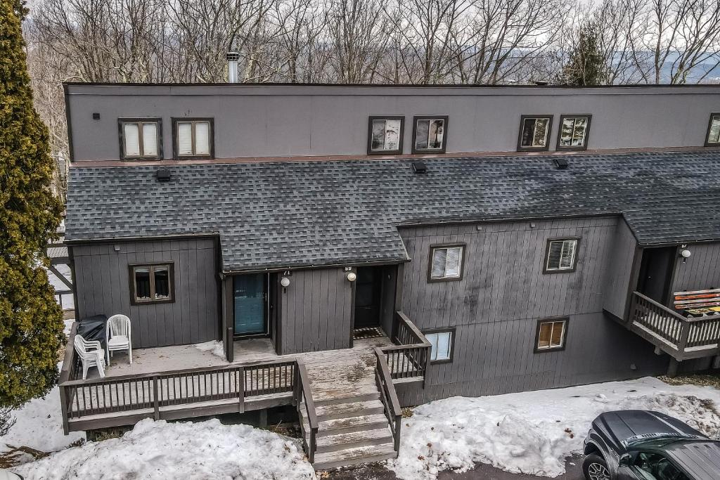 a gray house with a porch and stairs in the snow at Camelback 69 in Tannersville