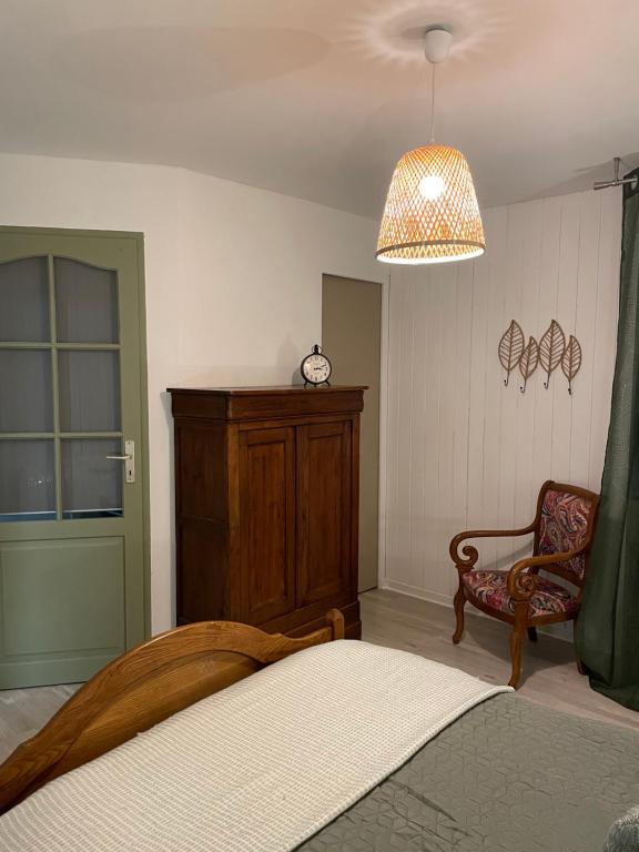 ein Schlafzimmer mit einem Bett, einem Stuhl und einer Uhr in der Unterkunft Les Hortensias de Marie in Laviéville