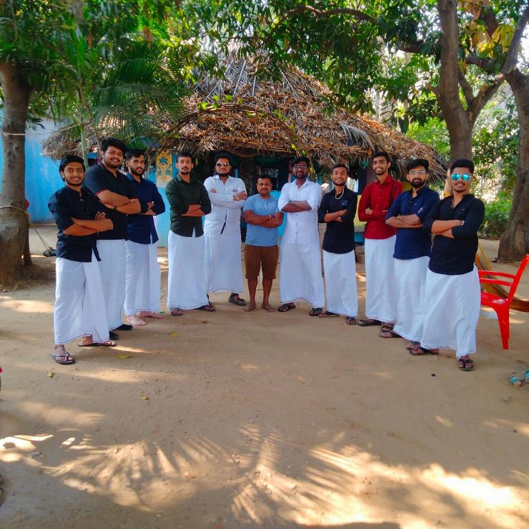a group of people standing in front of a building at GOLDENGARDEN COTTAGES in Hampi