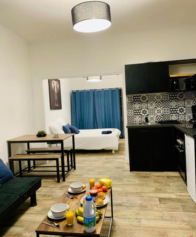 une cuisine et un salon avec une table avec de la nourriture dessus dans l'établissement L'Eden - Joli studio en centre ville, à Nîmes