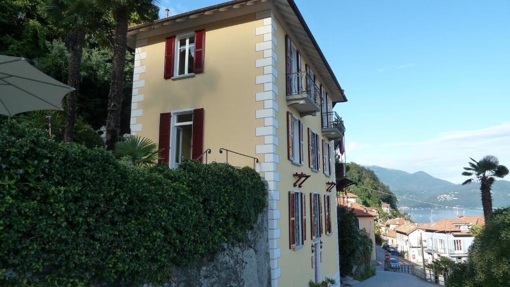 ein gelbes Gebäude mit roten Fenstern auf einem Hügel in der Unterkunft B&B Casa Forster in Cannero Riviera