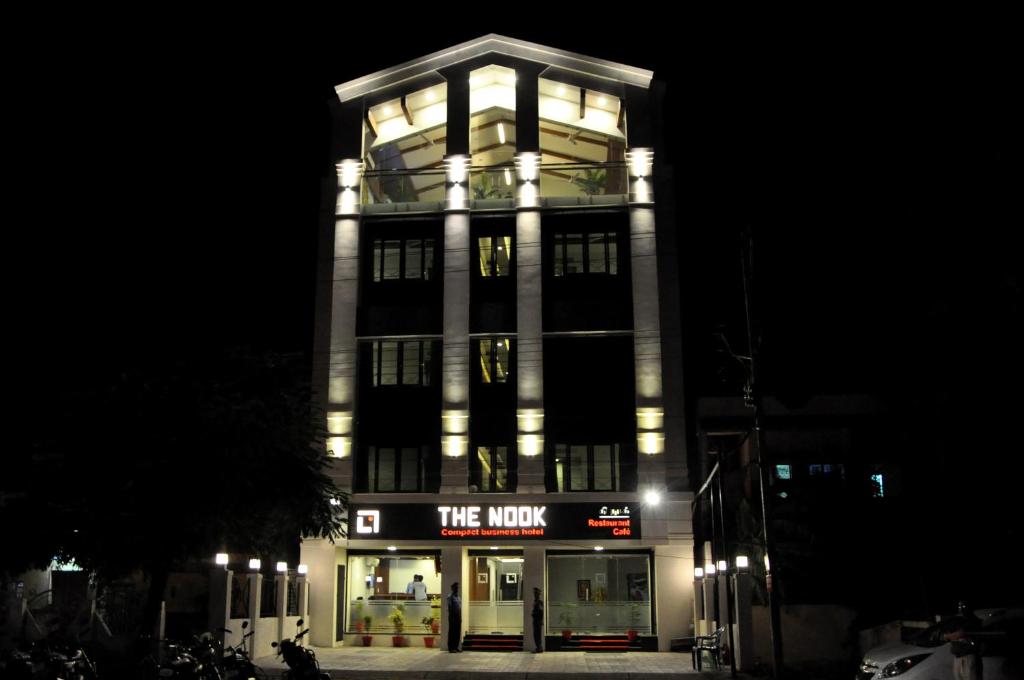 un edificio iluminado con una tienda por la noche en Hotel The Nook, en Madurai