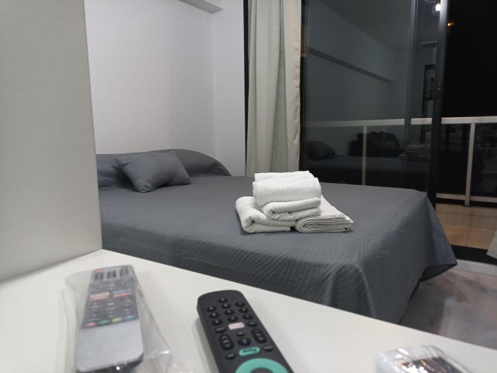 um quarto com uma cama com toalhas e um controlo remoto em Apart hermoso cerca del pulmón verde porteño - Alkyl House em Buenos Aires