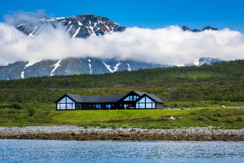 ein Haus auf einem Hügel mit einem Berg im Hintergrund in der Unterkunft Lyngen Experience Lodge in Nord-Lenangen