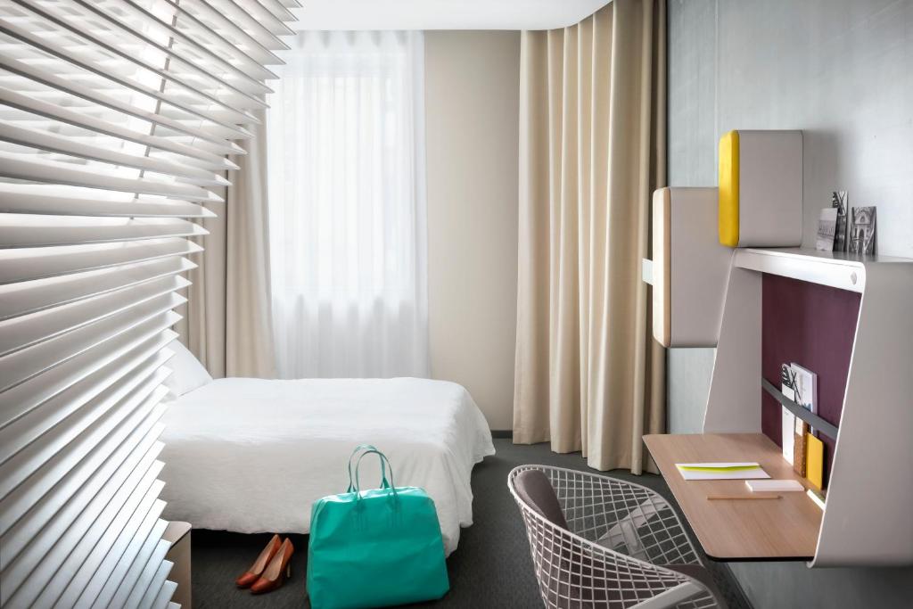 a hotel room with a bed, desk, and chair at Okko Hotels Lyon Pont Lafayette in Lyon