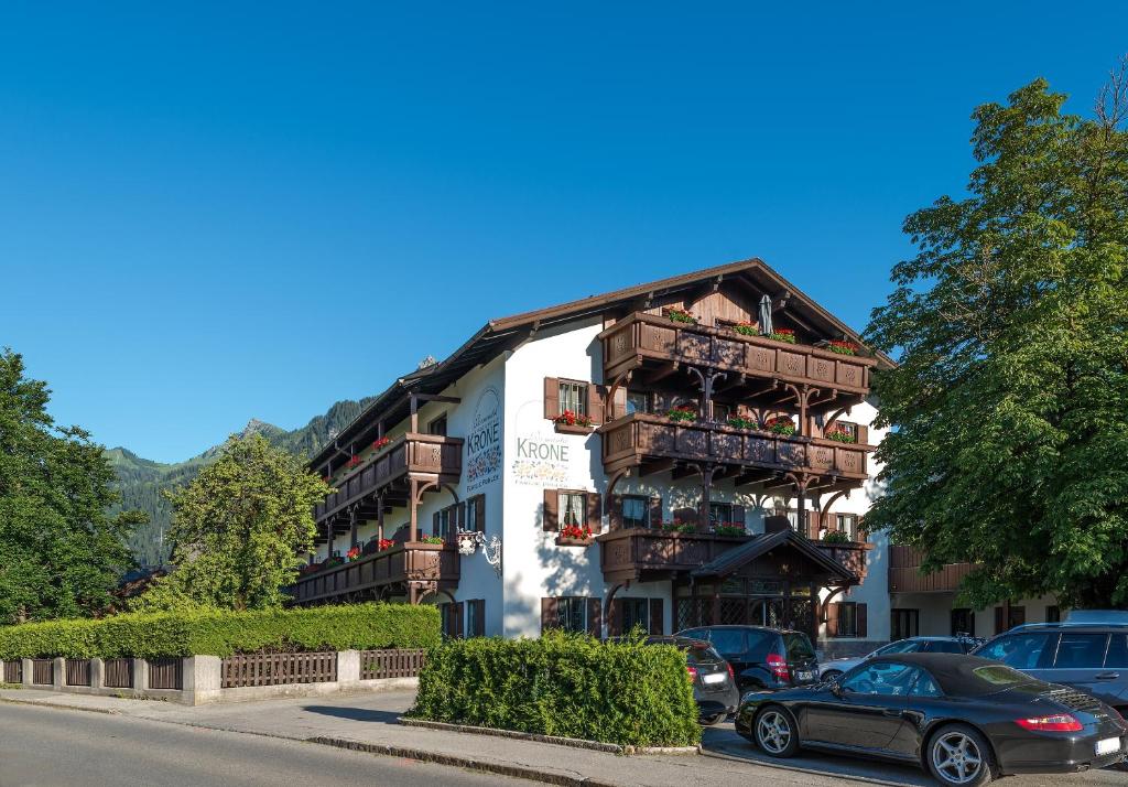 a building with balconies and cars parked in front of it at Hotel Krone Tirol in Reutte