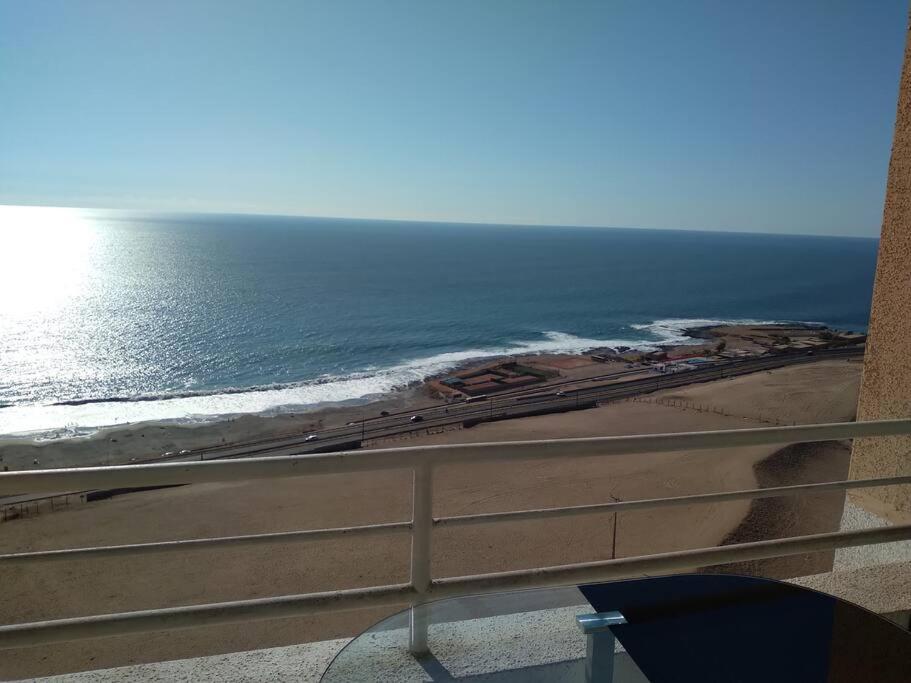 a view of the beach and the ocean from a balcony at Acogedor apartamento vista al mar in Iquique