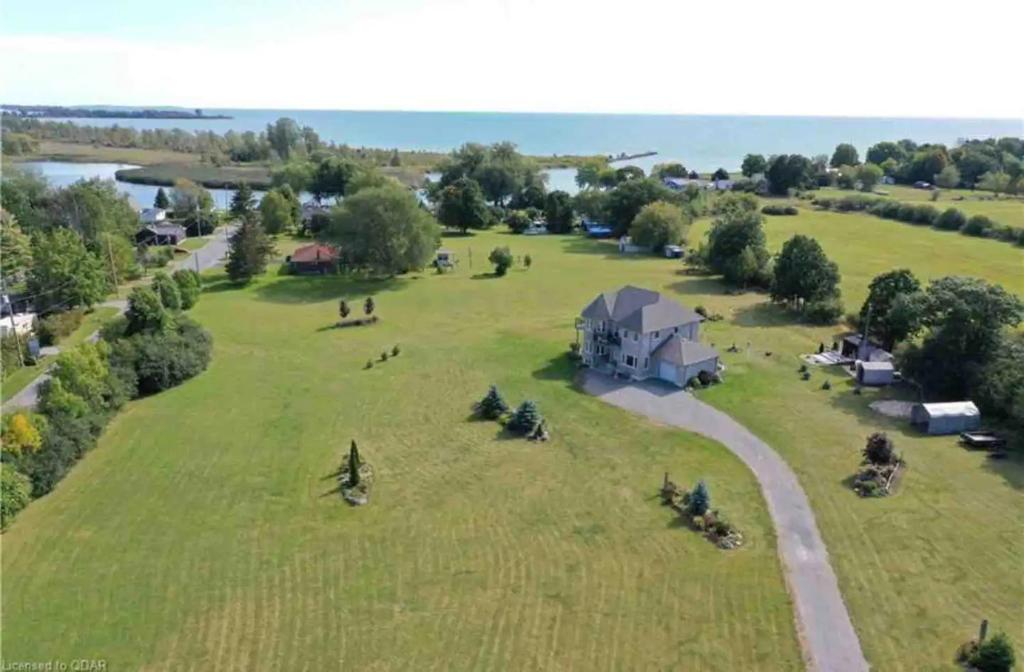 an aerial view of a large grassy field with a house at PlanURstay - Carrying Place 6BR & 3BTH Near SandBanks Park in Carrying Place