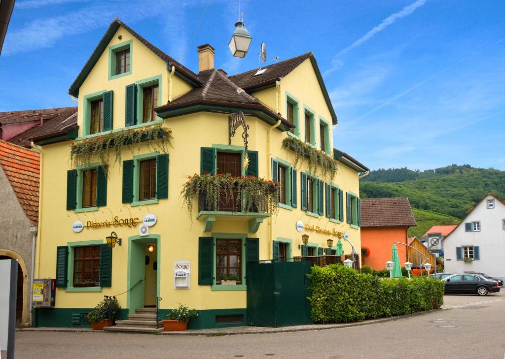 a yellow house with green shutters on a street at Hotel Sonne in Staufen im Breisgau
