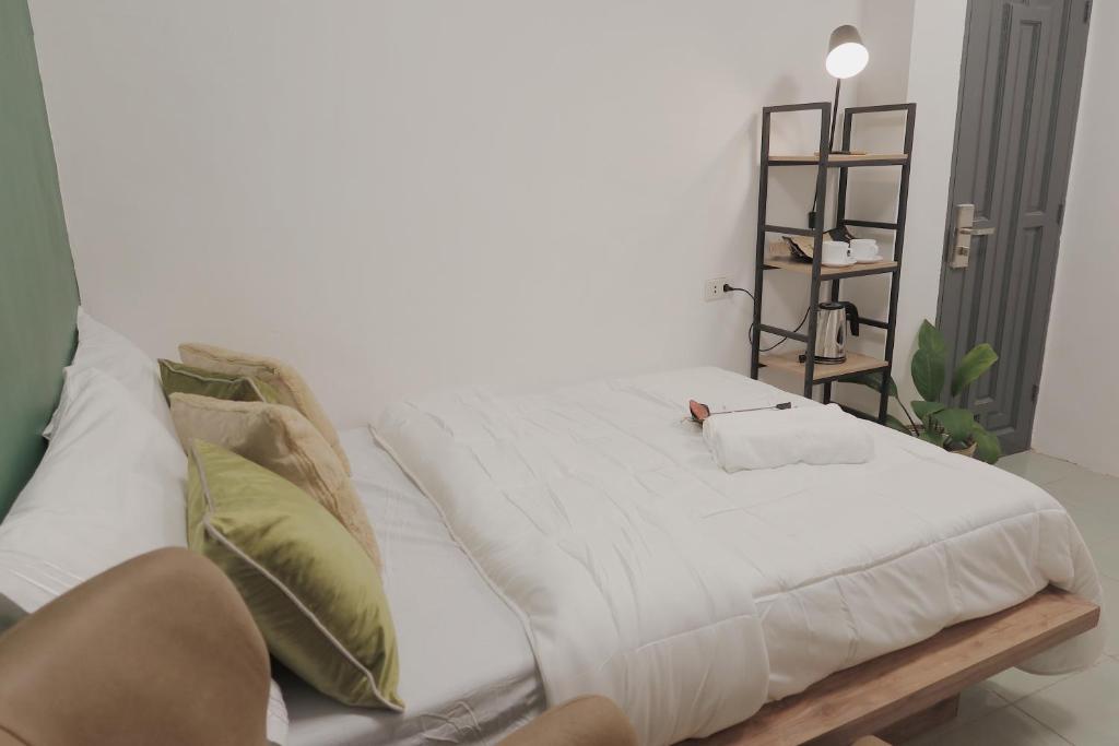 uma cama com lençóis brancos e almofadas num quarto em AJ Coffee & Bed em Coron