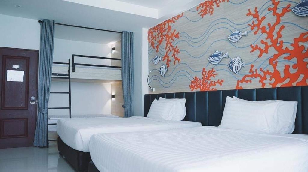 two beds in a room with a painting on the wall at Norn Talay Surin Beach Phuket in Surin Beach