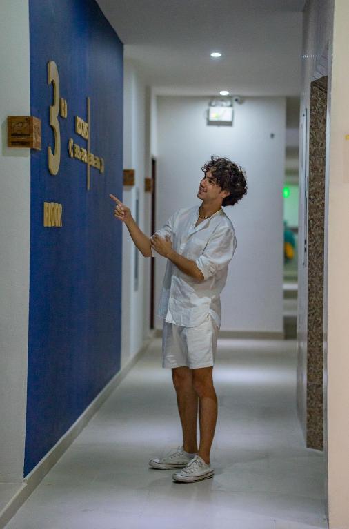 a man standing in a hallway pointing at a wall at Norn Talay Surin Beach Phuket in Surin Beach