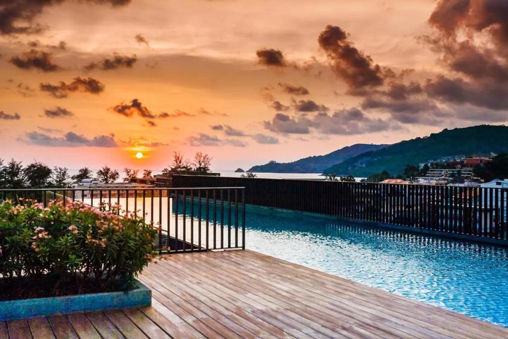 a wooden deck with a sunset in the background at The Deck patong Luxury Apartments The Deck patong in Patong Beach