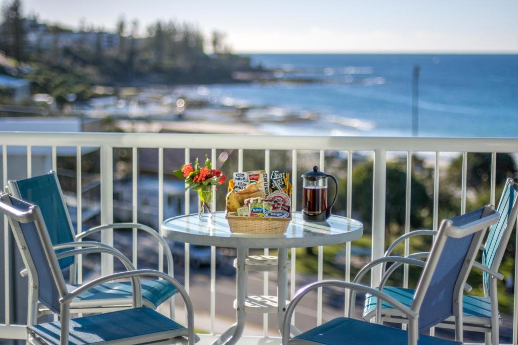 una mesa y sillas en un balcón con vistas al océano en Capeview Apartments - Right on Kings Beach, en Caloundra