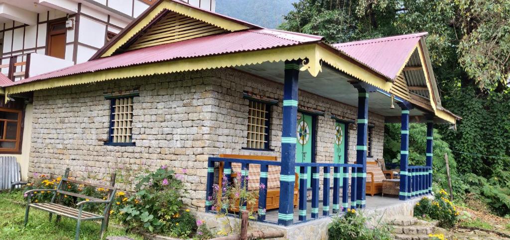 Daragaon Retreat (Gurung Homestay) في بيلينغ: منزل صغير بسقف احمر ومقعد