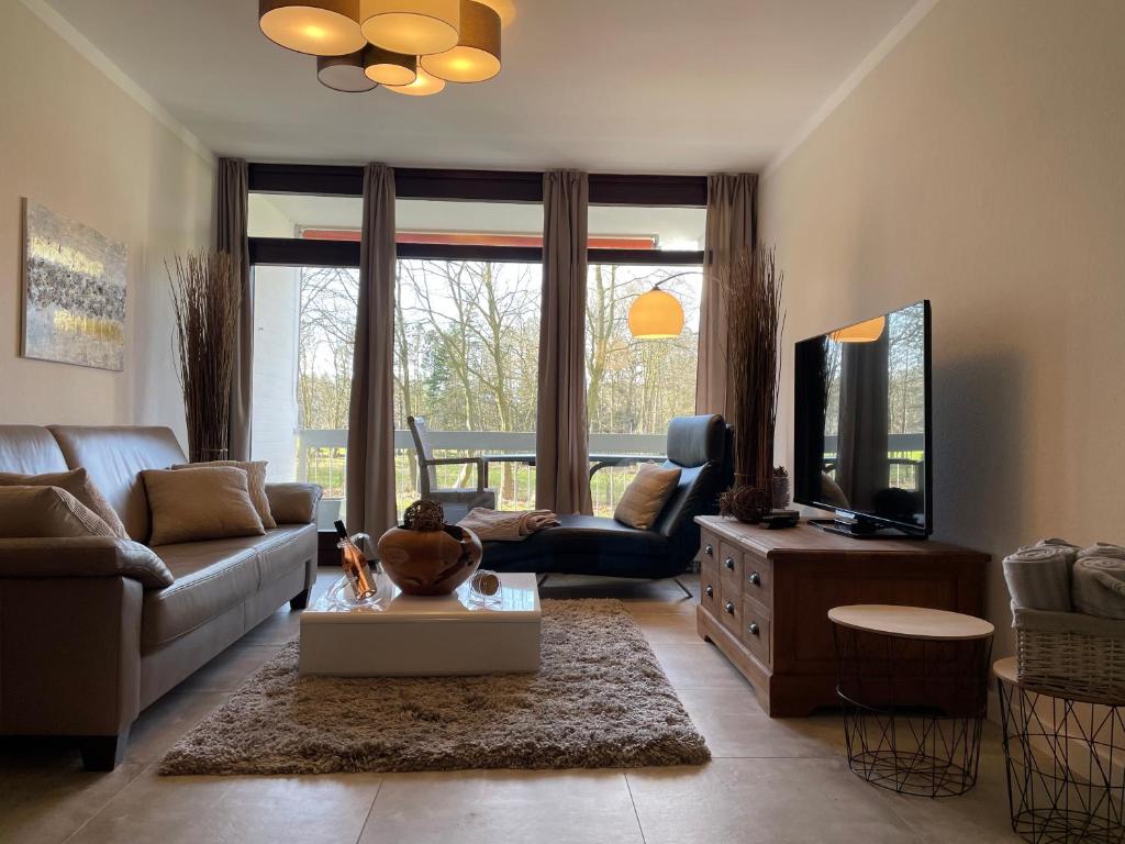 ein Wohnzimmer mit einem Sofa und einem TV in der Unterkunft Moderne Ferienwohnung / Top City- u. Wasserlage am Yachthafen Bad Zwischenahn in Bad Zwischenahn