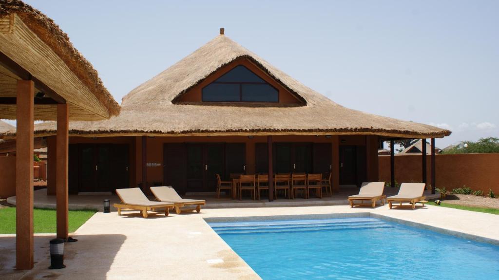 un complejo con techo de paja y piscina en Villa Rebecca, en Nianing