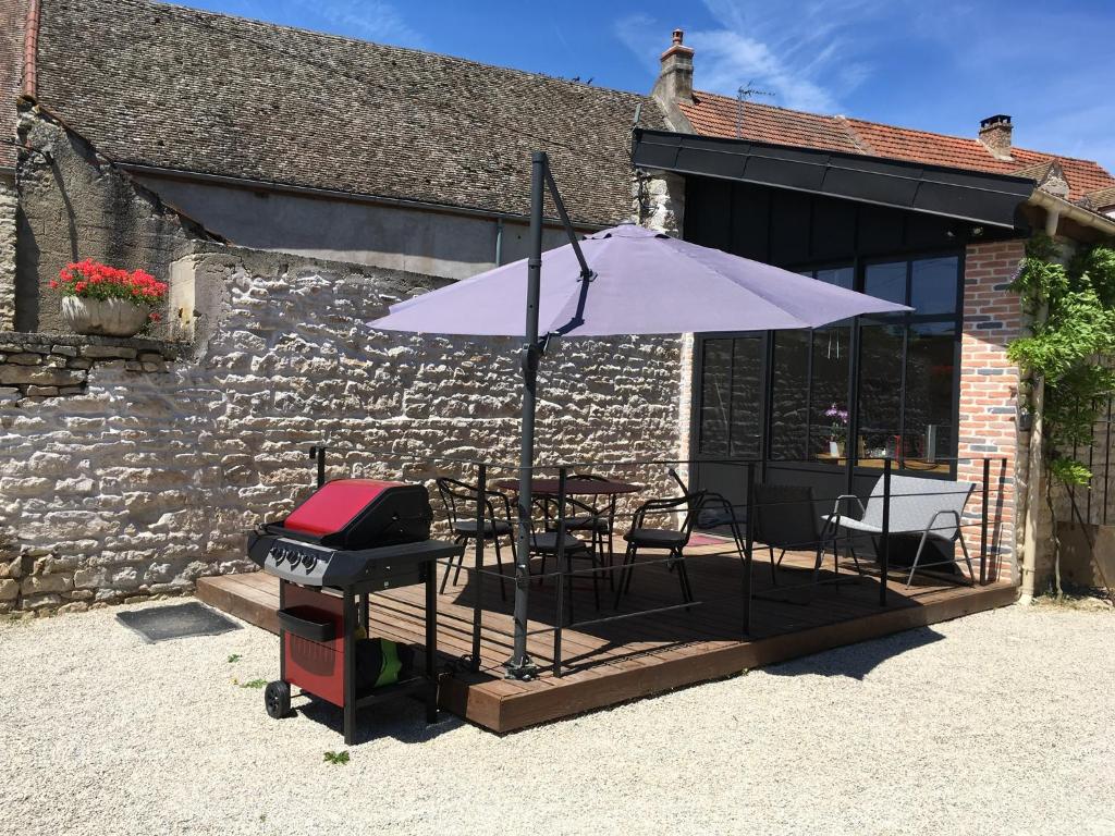 a grill and an umbrella on a patio at L'Atelier 1 in Corcelles-les-Arts