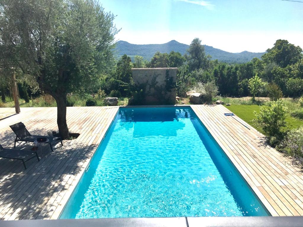 una piscina en un patio con terraza de madera en VILLA privée 3 étoiles avec piscine, jardin et terrain de pétanque en Lecci